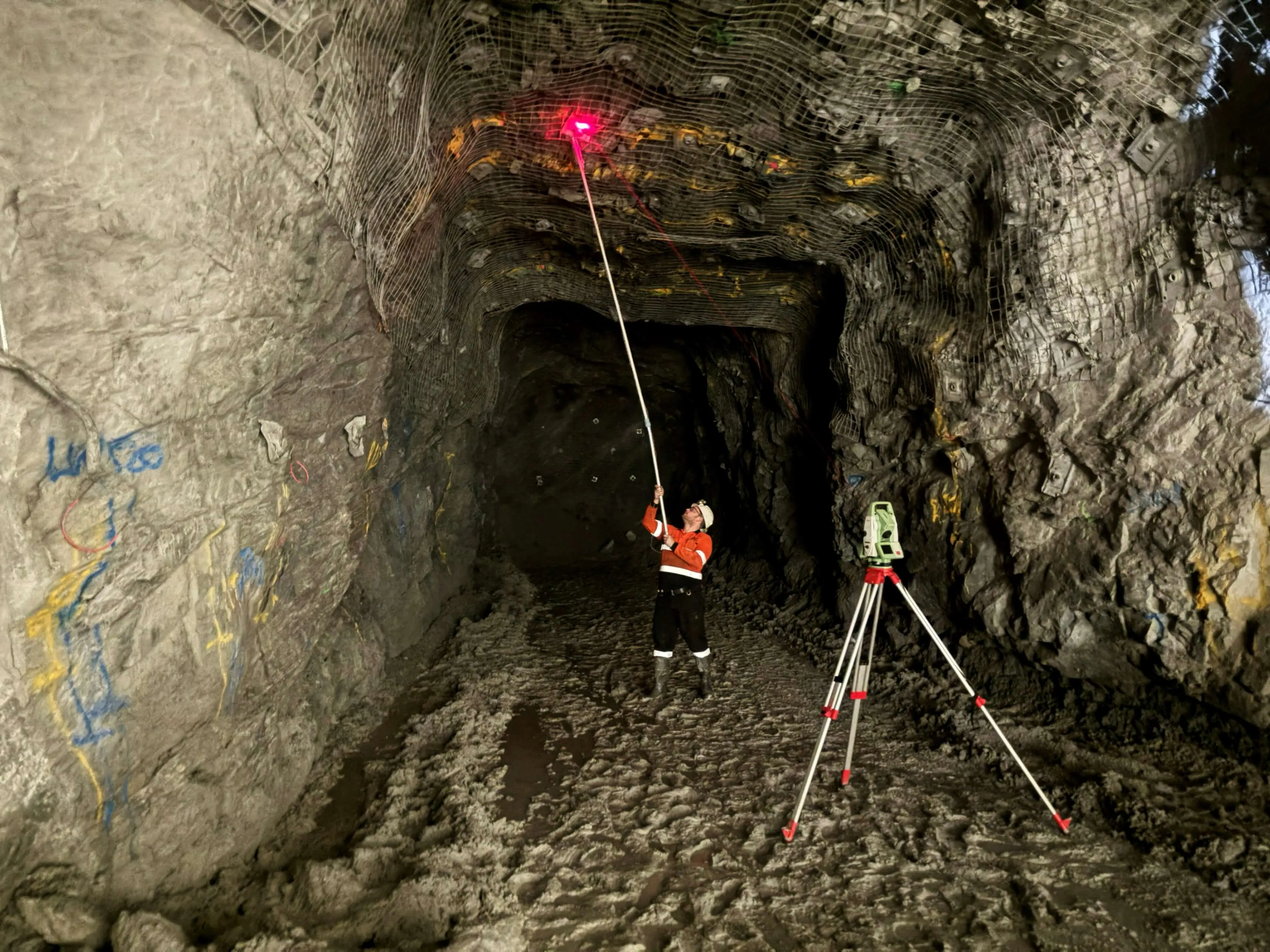 Green LED OptiClino marker pucks mounted on a drill boom, illuminated in an underground drive