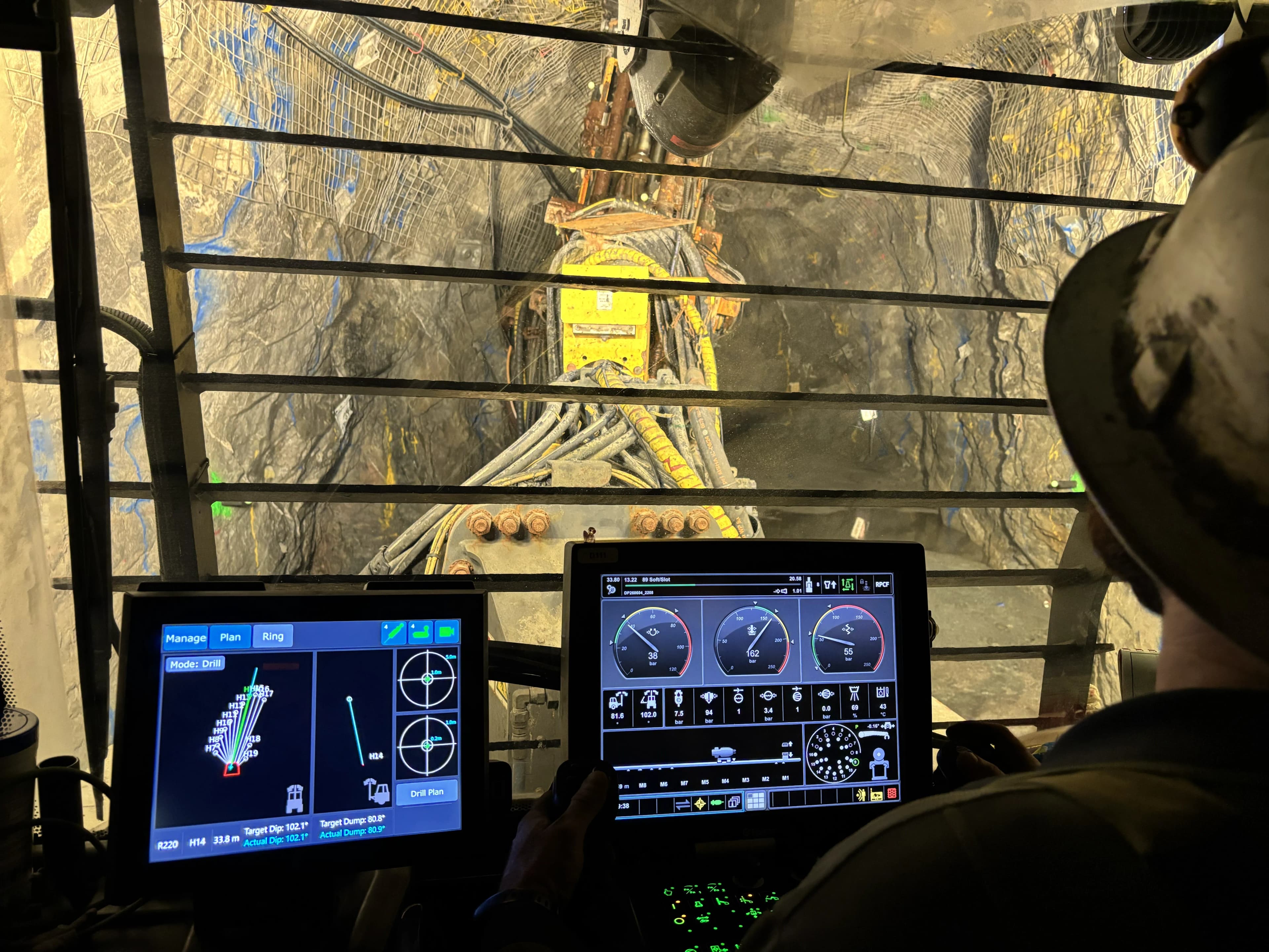 Drill rig boom extended in an underground tunnel with green OptiClino markers illuminated